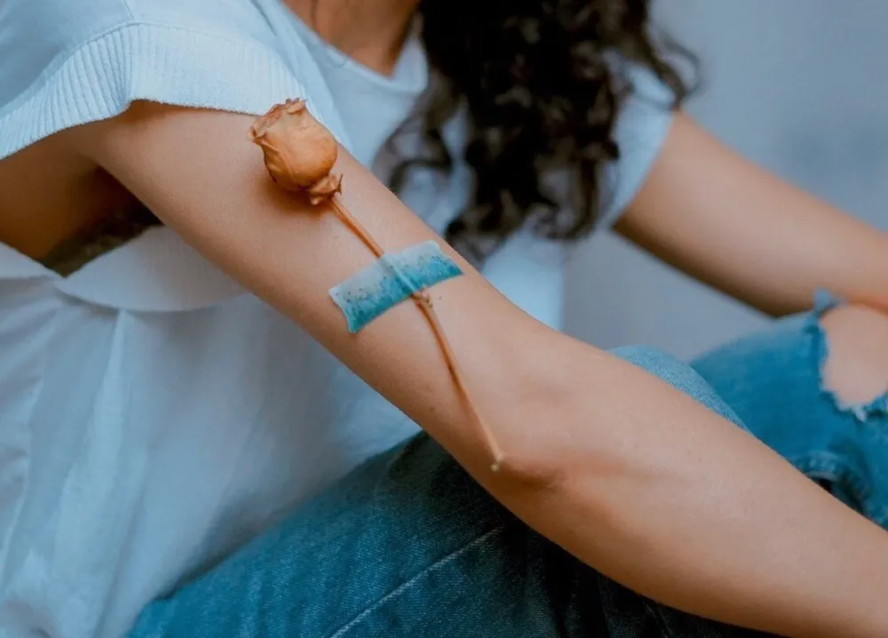 Close-up of a woman's arm with a dried rose laid along it